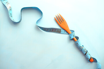 fork with measurement tape on blue background 