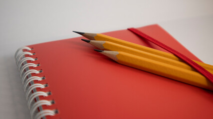 Tree yellow pencils on red notebook with white background