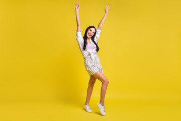 Fototapeta na wymiar Full size photo of young pretty excited smiling positive girl dancing raise fists up isolated on yellow color background
