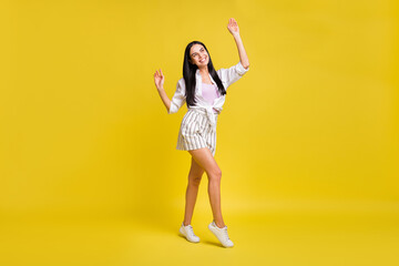 Full size photo of young excited smiling positive dreamy girl look copyspace dancing isolated on yellow color background