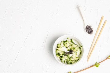 Fresh cucumber salad with sesame seeds in a white ceramic bowl