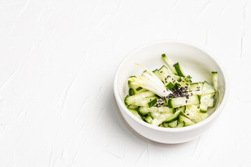 Fresh cucumber salad with sesame seeds in a white ceramic bowl