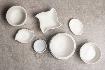 Assorted white empty bowls and plates on a stone background