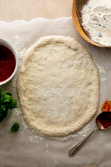 Pizza coooking process with sourdough homemade natural east dough, top view, tomatoes sauce and basil