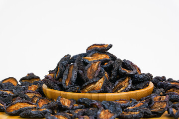 Dried plums on white background. Organic dried  fruits. Natural dry prunes in wooden bowl.  Studio light. Copy space. Health, organic concept.