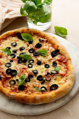 Homemade pizza ham, black olives, cheese and fresh basil. Sourdough pizza.