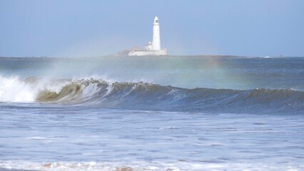 Wavebow / rainbow in waves with Lighthouse behind 
