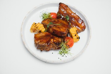 Delicious grilled pork ribs in BBQ sauce with herbs, isolated on white background