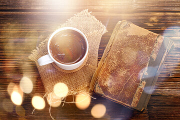 Old book and cup of coffee on wooden background