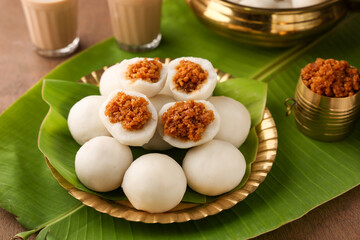 Kozhukatta Pidi in golden plate Indian milk tea Kerala tea time snack steamed food sweet modak rice dumpling Ganesh Festival India sweet food stuffed grated coconut jaggery christian food Palm sunday 