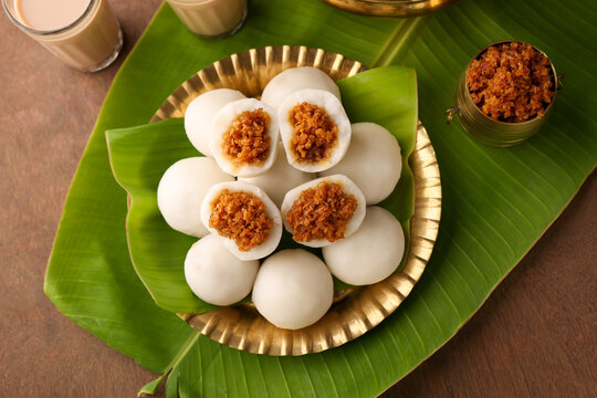 Kozhukatta Pidi in golden plate Indian milk tea Kerala tea time snack steamed food sweet modak rice dumpling Ganesh Festival India sweet food stuffed grated coconut jaggery christian food Palm sunday 