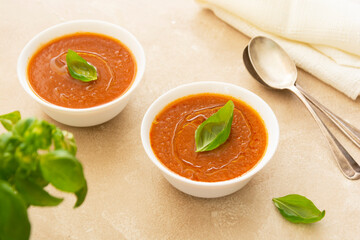 Gazpacho cold tomato soup bowl with basil, bright background.