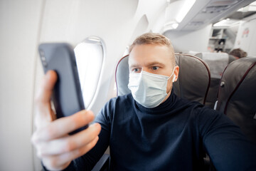 Fototapeta na wymiar Male with safe mask passenger of airplane use mobile phone in chair. Concept travel covid