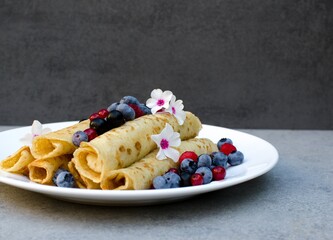 Morning breakfast with pancakes, fresh blueberries in a plate decorated with fresh berries, on a gray background, close-up. Healthy breakfast concept