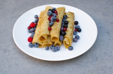 Morning breakfast with pancakes, fresh blueberries in a plate decorated with fresh berries, on a gray background, close-up. Healthy breakfast concept