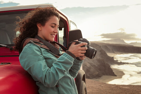 Beautiful young woman doing a road trip in the nature, driving an old off-road car