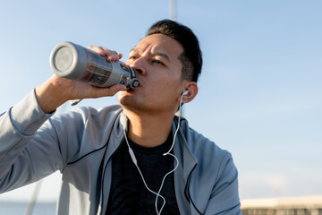 Thirsty man drinking water after exercise outdoors.