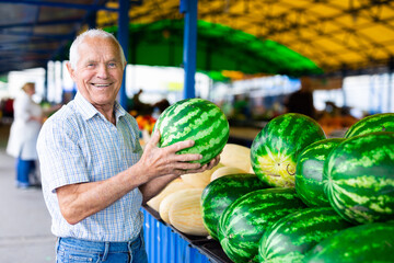 retired european man buys melons and watermelons in market