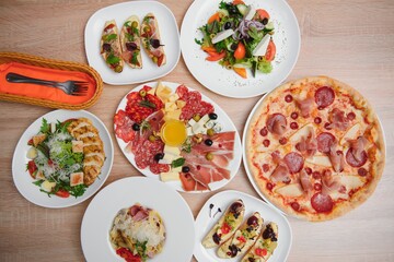 Fototapeta na wymiar Different salads on wooden table, top view. Vegetable salad, Salad with smoked duck, Grilled chicken Caesar salad.