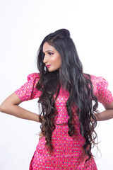 Naklejka premium Young Indian girl posing in a studio for a model shoot wearing a pink coloured traditional and ethnic dress called sharara