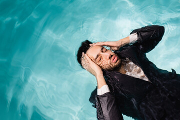 Top view of arabian businessman with hands near head swimming in pool