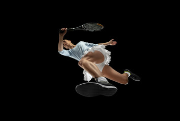 Female professional tennis player in action, motion isolated on black background, look from the...