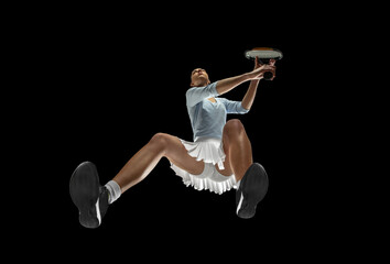 Female professional tennis player in action, motion isolated on black background, look from the...