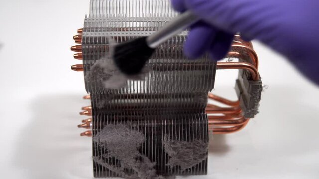 The master repairman with a brush cleans dust from the heatsink of the PC central processor cooling. Home pc maintenance and upgrade