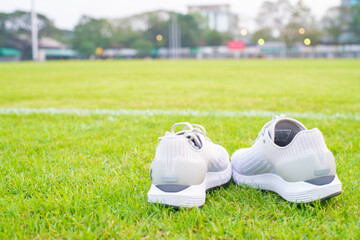 White running shoe on green football grass field
