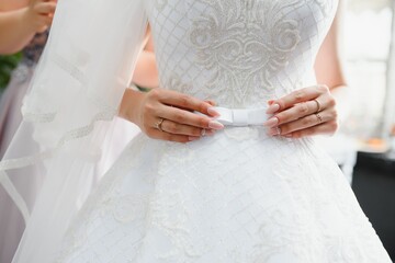 Bridal morning, bride wears dress. Groom helping fiancee to get dressed, adjusting buttons on wedding gown, rear view. close-up, crop
