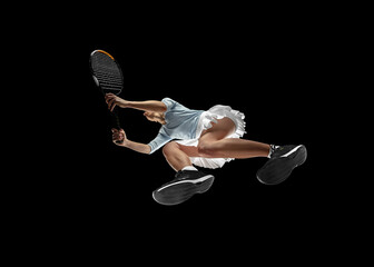 Female professional tennis player in action, motion isolated on black background, look from the...