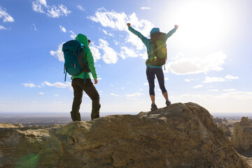 Two successful women backpackers hiking on sand desert