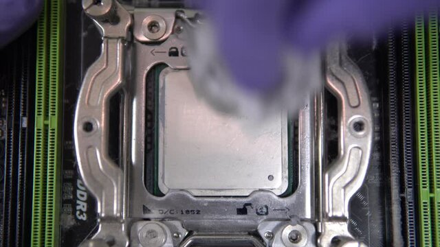 The repairman wipes off the thermal grease from the main processor with a tissue. Maintenance and upgrade of a personal computer