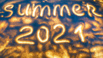 the inscription on the sand summer 2021 glows.