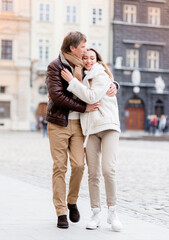 Front view of young couple walks around the city and hugs each other. Concept of a romantic relationship