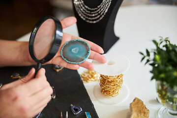 Female master examining a gemstone slice for flaws
