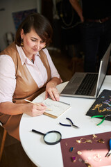 Pleased jewelry designer concentrated on her work