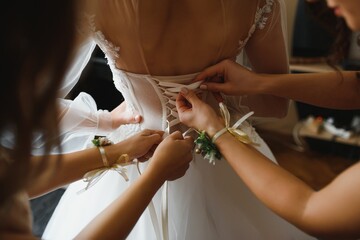 Bridal morning, bride wears dress. Groom helping fiancee to get dressed, adjusting buttons on wedding gown, rear view. close-up, crop