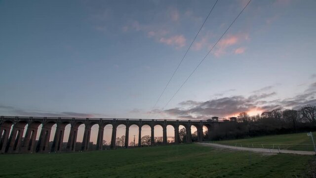 Time-lapse of clouds passing by over Ouse Viaduct at sunset. Static wide shot.