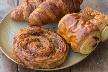 Traditional french croissants, buns with chocolates on rustic plate close up