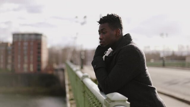 Thoughtful black African man thinking about life on top of a bridge
