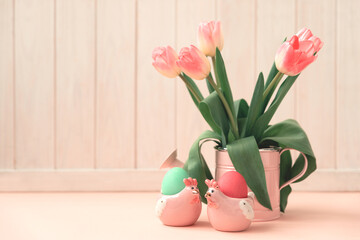 Easter eggs, ceramic hen and wase with tulips on pink wooden table. Easter celebration concept. Soft focus. Copy space
