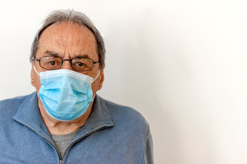Old man with foggy eye glasses due to condensation caused by the use of a protective face mask. Senior man with foggy glasses. The effects of wearing a mask for people that must wear glasses.
