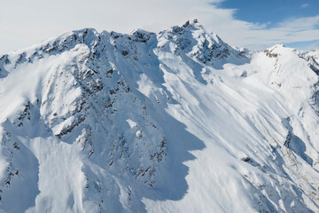 Aerial view of Elbrus and Cheget mountains in snow in winter upon the clouds, climbing and mountain skiing