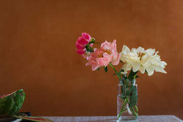 bouquet of pink peony flowers of different shades in jar on kitchen table. tree peon and watermelon.