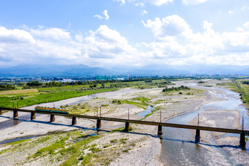 北アルプスを背景に常願寺川を渡る富山地方鉄道本線の普通列車	