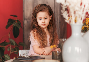 A little sad girl sits at the kitchen table. Waiting for lunch
