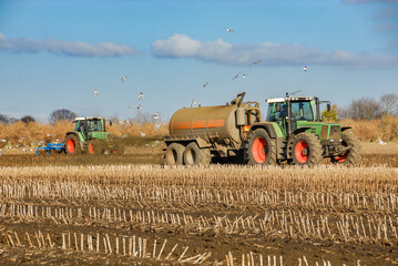 Agricultural machinery fertilising and ploughing in the field