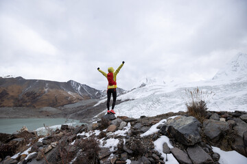 Successful woman trail runner open arms to winter fossil glacier snow mountains