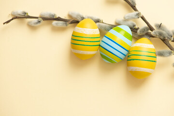 Close up Easter colorful eggs and branches on light beige pastel background with space for text. pussy willow branches.Easter decoration, Spring holiday festive card. fluffy wool